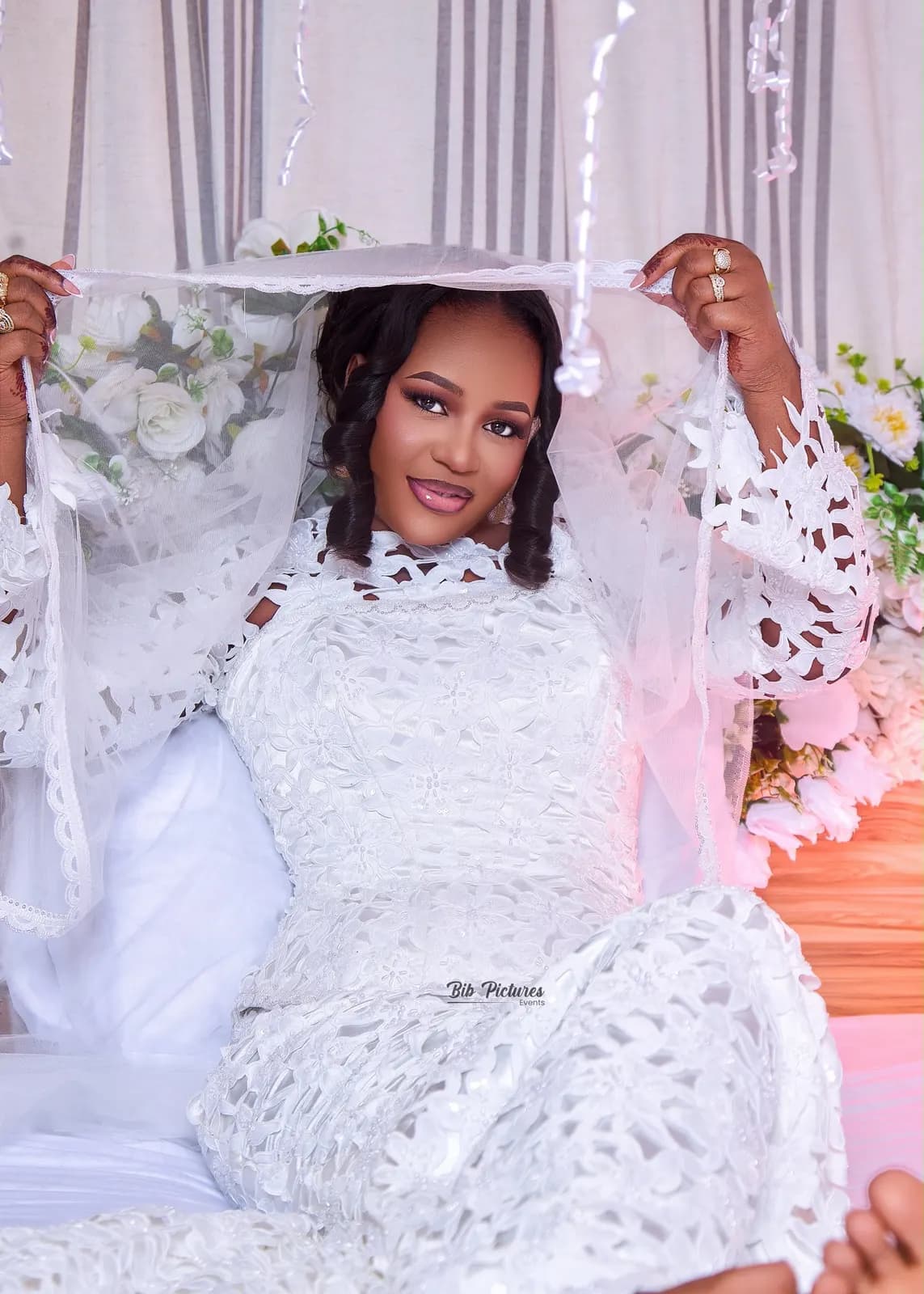 Mariée en robe de dentelle blanche et voile, mains au henné.