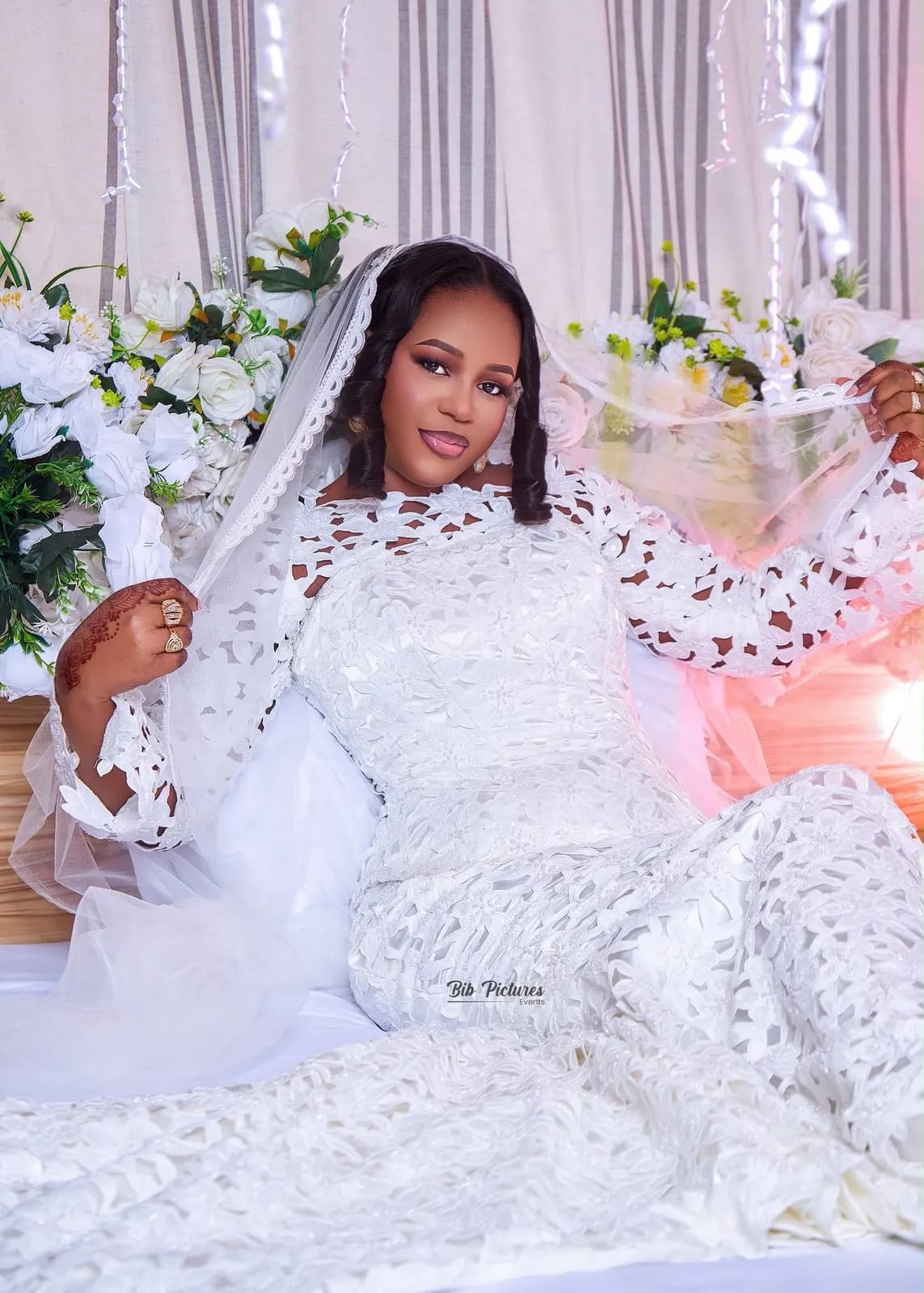 Mariée en robe de dentelle blanche et voile, mains au henné.