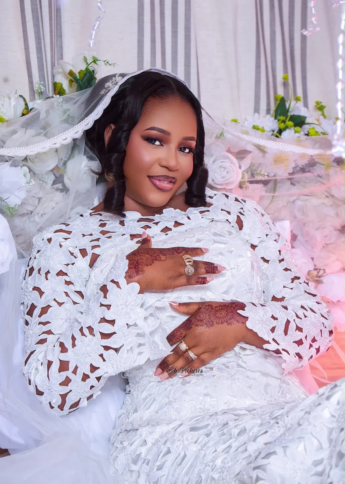 Mariée en robe de dentelle blanche et voile, mains au henné.