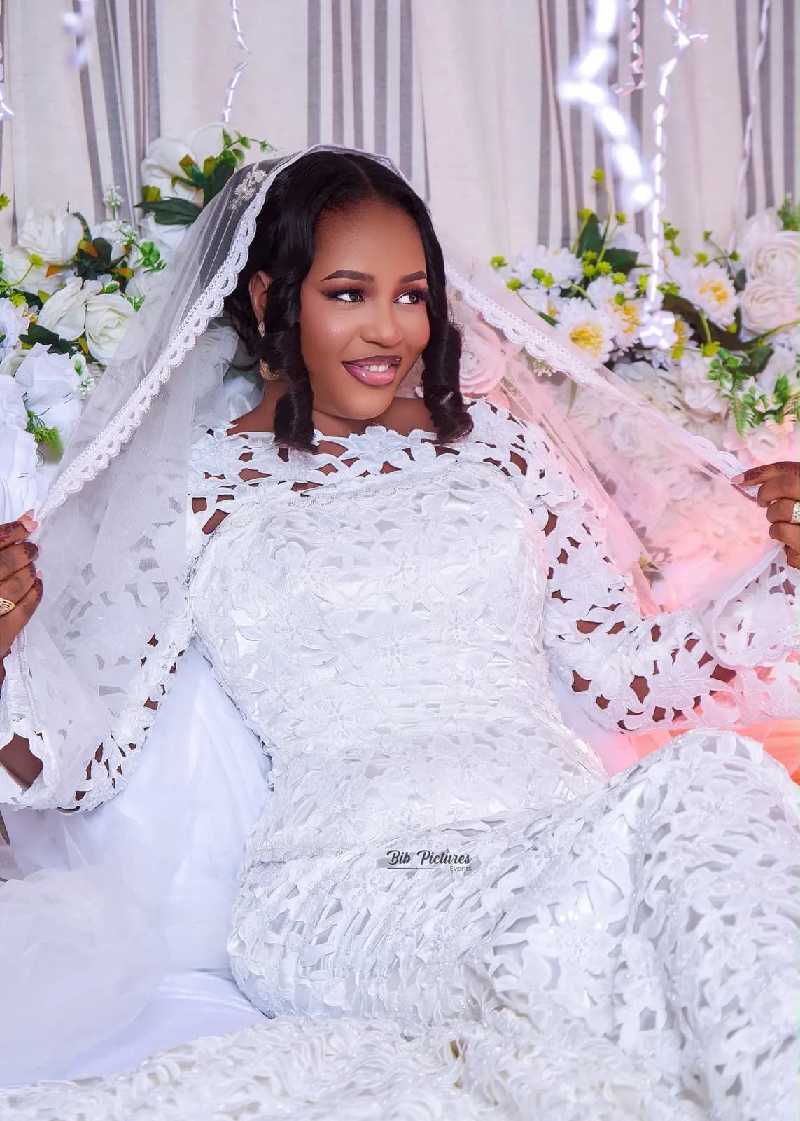 Mariée en robe de dentelle blanche et voile, mains au henné.